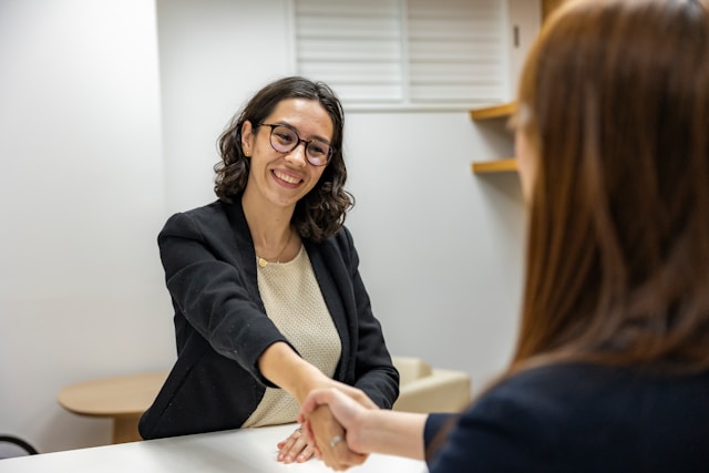 Colloquio di lavoro tra recruiter e candidata con stretta di mano dopo confronto sul range retributivo
